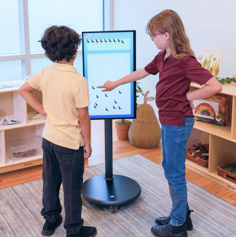 Two children using the Muv Pro mobile screen to play a touch screen game