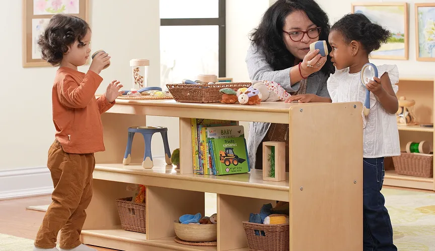 Teacher in a preschool classroom playing with children around a Carolina Birch shelving unit