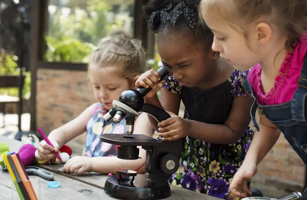 Group of children outside looking through a magnifying glass