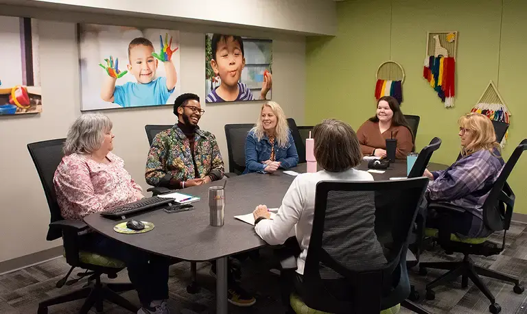 Group of Kaplan employees meeting around a conference table