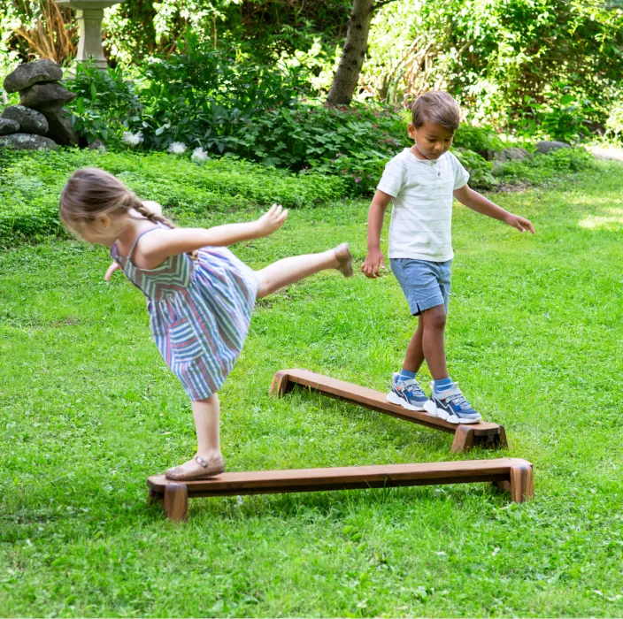 Children outside playing on wooden balance beams