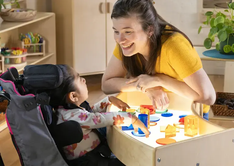 Preschool teacher interacting with a special needs child at the Carolina Connections Discovery Table