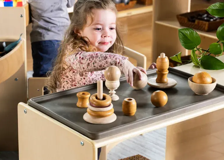 Young child playing with wooden shaped toys on a Carolina Connections Inclusive Mat