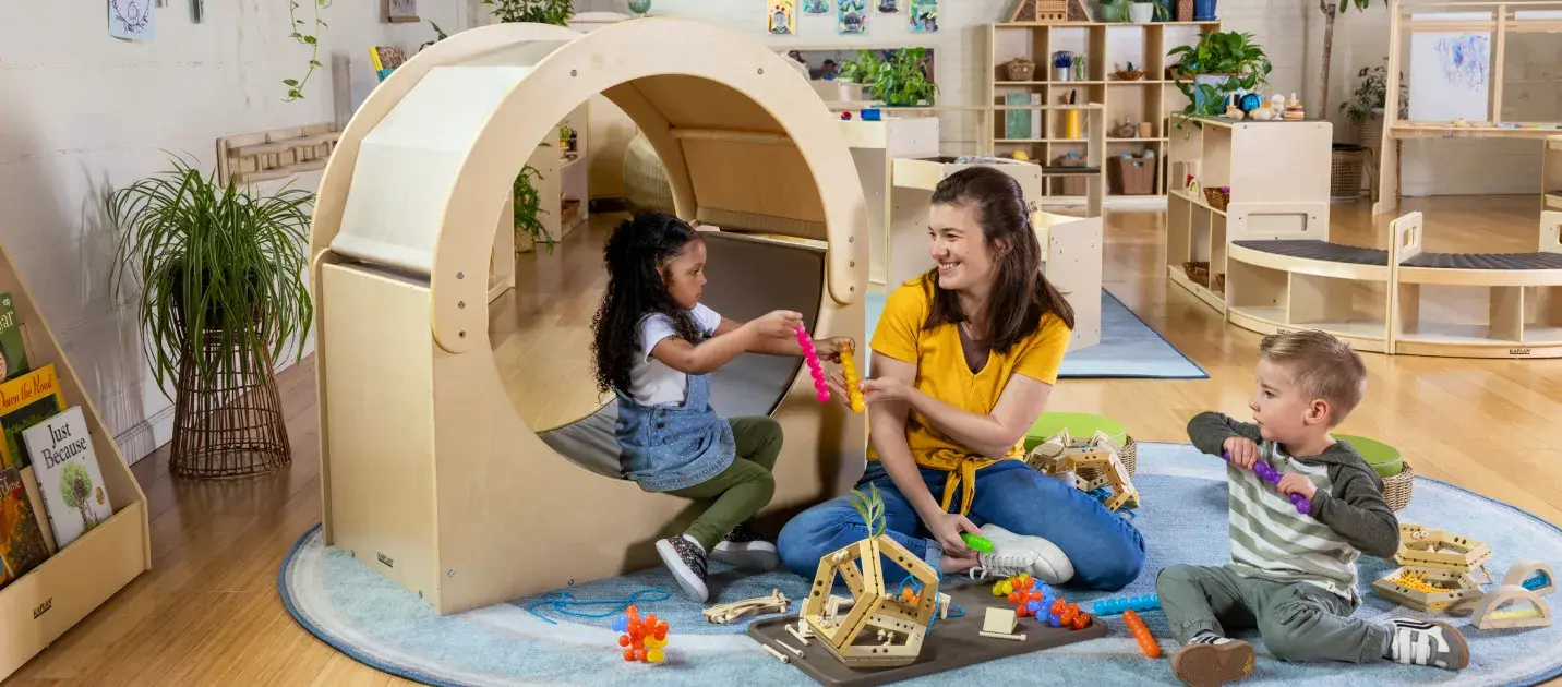 Teacher in a preschool classroom playing with children using Carolina Connections furniture