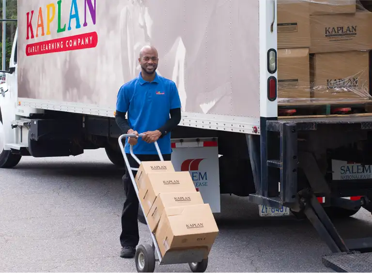 Kaplan delivery person unpacking a large delivery truck in the parking lot of an early childcare center