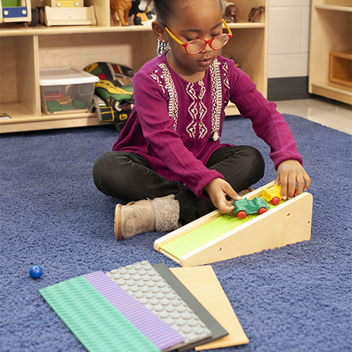 Student Playing with Car Ramp Toy