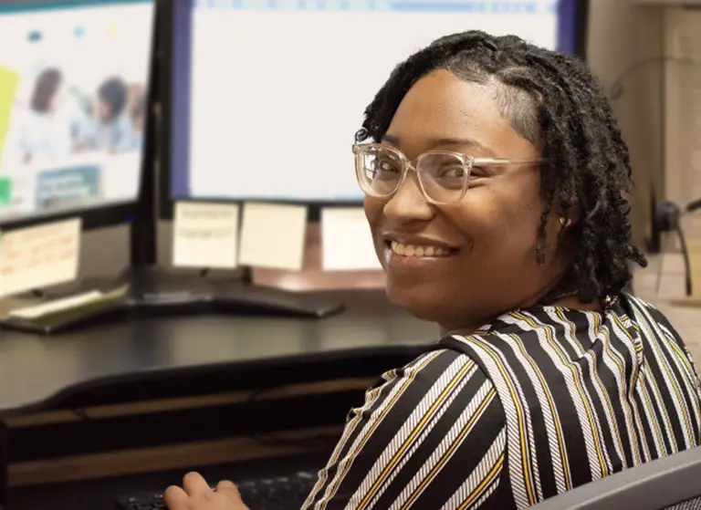 Customer service representative sitting at a computer smiling