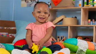 Infant child siting up on a playmat smiling