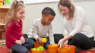 Children and teacher playing with fake vegetables