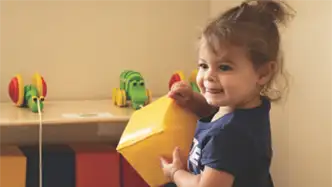 child holding a large block smiling