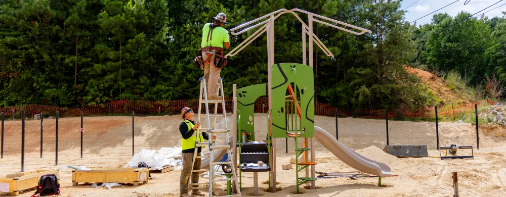 Workers assembling a playground structure at a construction site