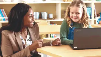 Teacher helping a child on a laoptop computer