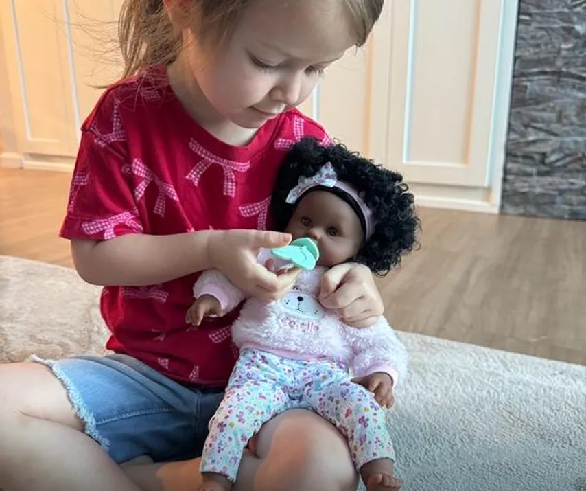 Girl playing with Bebe Calin Caroline 12 inch Doll