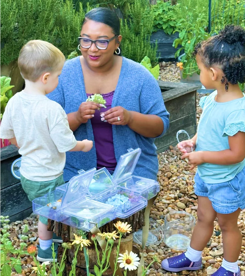 Children and teacher playing outdoors around a wooden table
