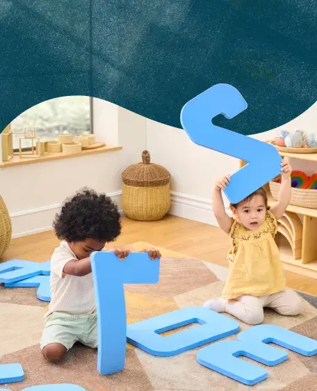 Two toddlers playing with large foam numbers on the floor