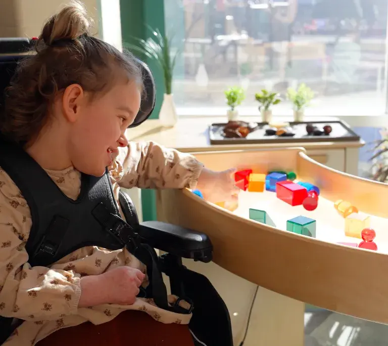 Girl playing with colorful blocks on a curved light table