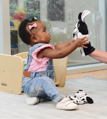 Baby interacting with a rabbit puppet on the hand of an adult