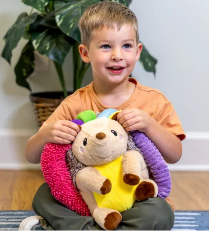 Young child holding a multicolored porcupine stuffed toy