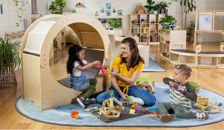 Teacher in a preschool classroom playing with children using Carolina Connections furniture