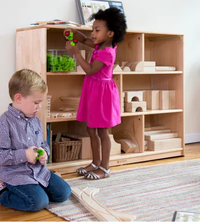 Children taking toys from a shelving unit