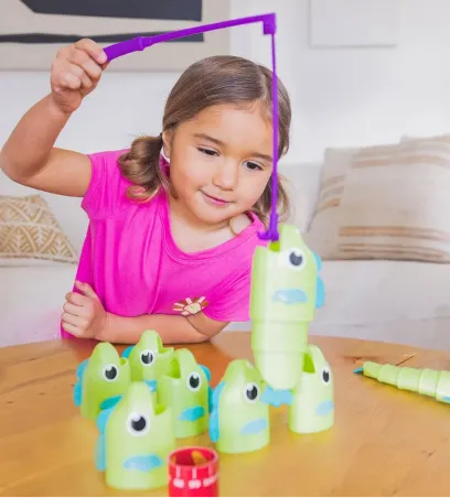 Girl using a toy fishing set to count fish on a table