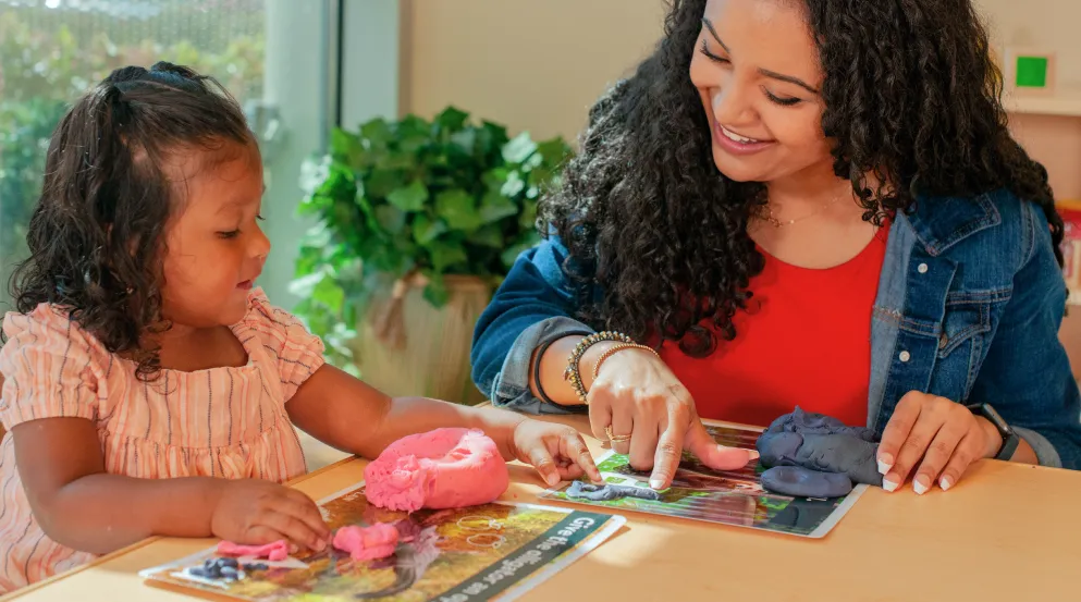 Preschool teacher with child using modeling clay