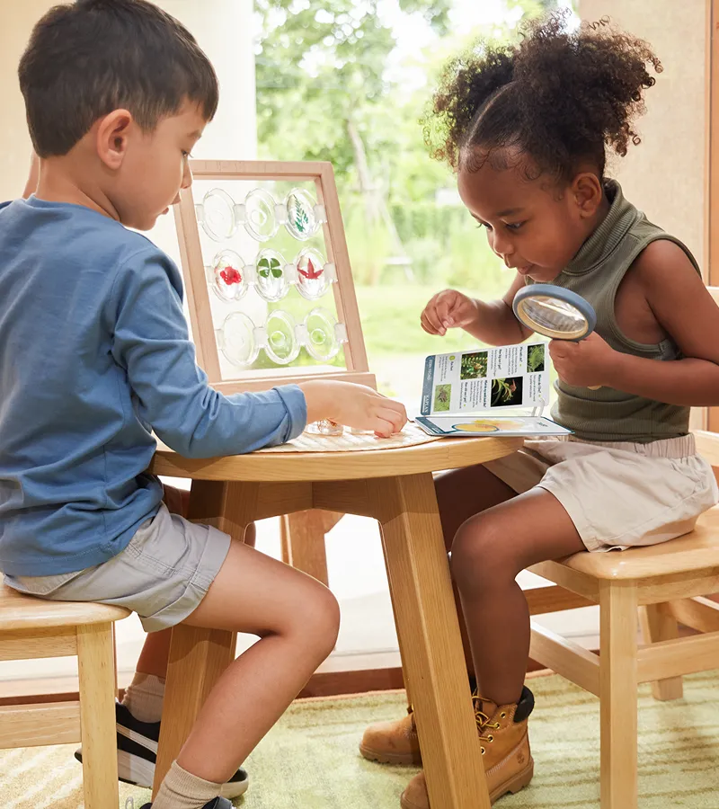 Children looking at science books around a table