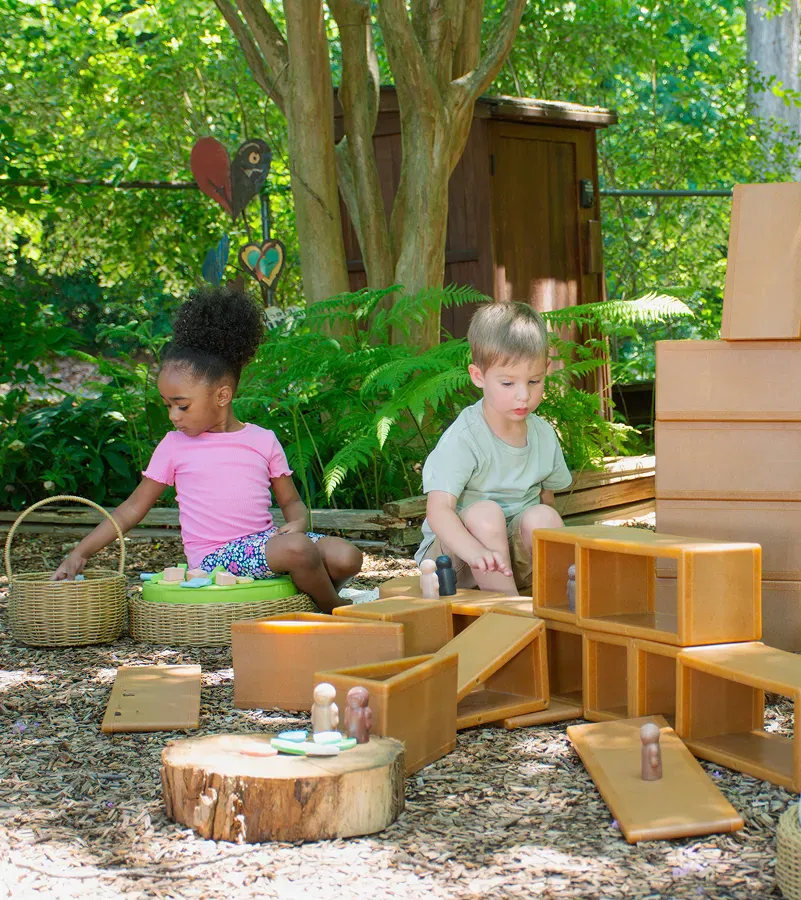 Children and teacher playing outdoors around a wooden table