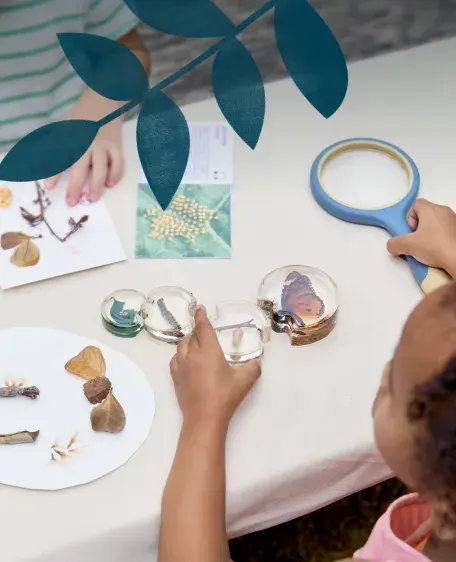 Child using a magnifying glass to look at puzzle pieces with various nature objects printed on them